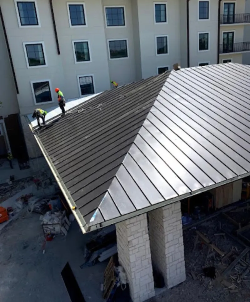 Crew installing standing seam metal roof panels on a commercial project in Euless